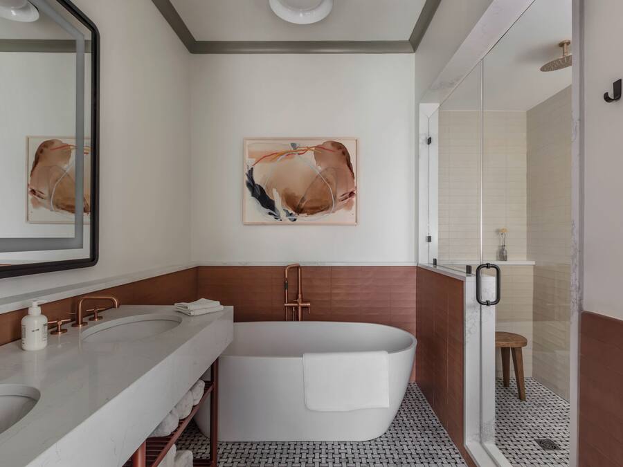 A modern bathroom with a large bathtub, two sinks, and a glass shower enclosure.