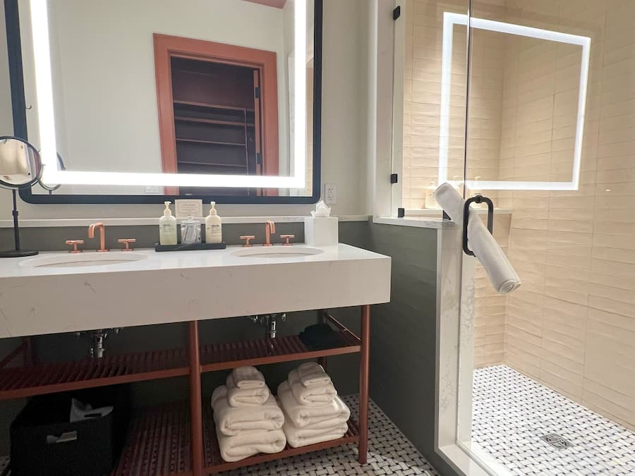 A bathroom with a large mirror, white sink, and a glass shower enclosure.
