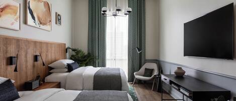 A modern hotel room with two beds, a desk, a TV, and artwork on the walls.