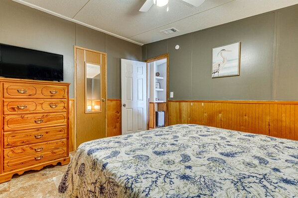 Een slaapkamer met een bed, een dressoir, een televisie en een deur naar een badkamer.