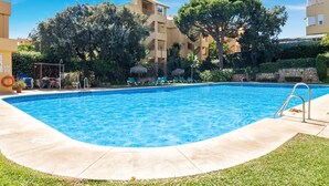 Una piscina de agua cristalina y azul, rodeada de césped y árboles.