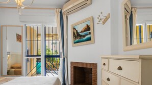 Un dormitorio con cama, chimenea, tocador, un cuadro y un balcón con vistas.