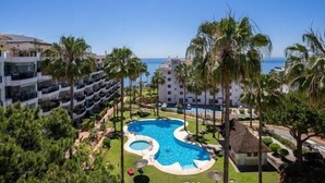 A resort with a large pool, palm trees, and a view of the ocean. - 1370 Mi Capricho Calahonda Holiday Rental (Mijas)