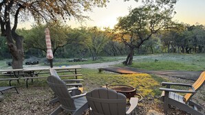 Un espace extérieur aménagé avec des chaises Adirondack, un barbecue et des tables de pique-nique.