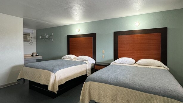 Ein Hotelzimmer mit zwei Betten, einem kleinen Schreibtisch und einer Wandleuchte.
