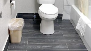 Ein kleines Badezimmer mit Toilette, Mülleimer, Handtuchhalter und Badewanne.