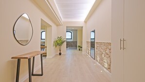 A hallway with a wooden bench, a potted plant, and a stone wall.
