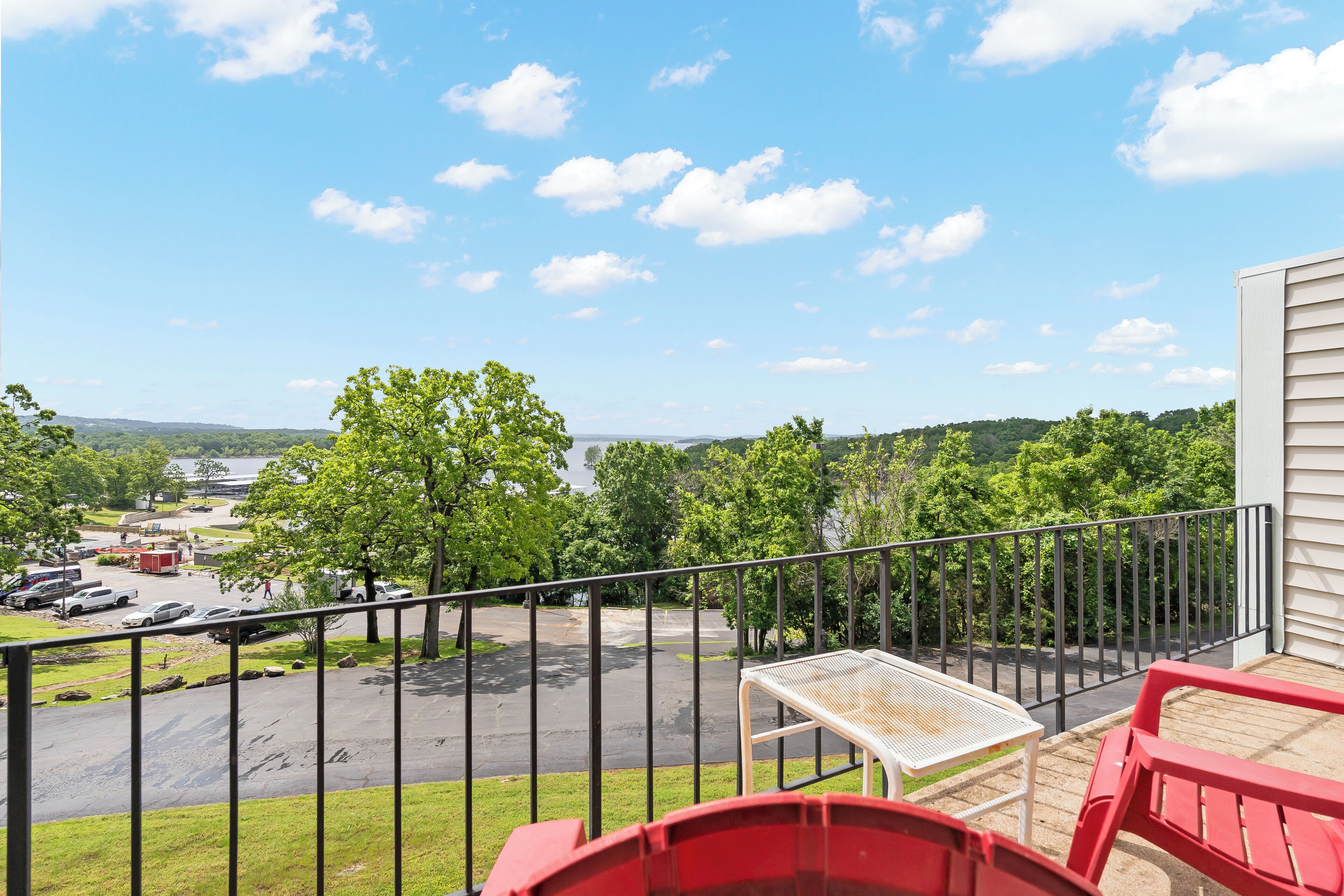 A balcony with a view of a parking lot and trees.