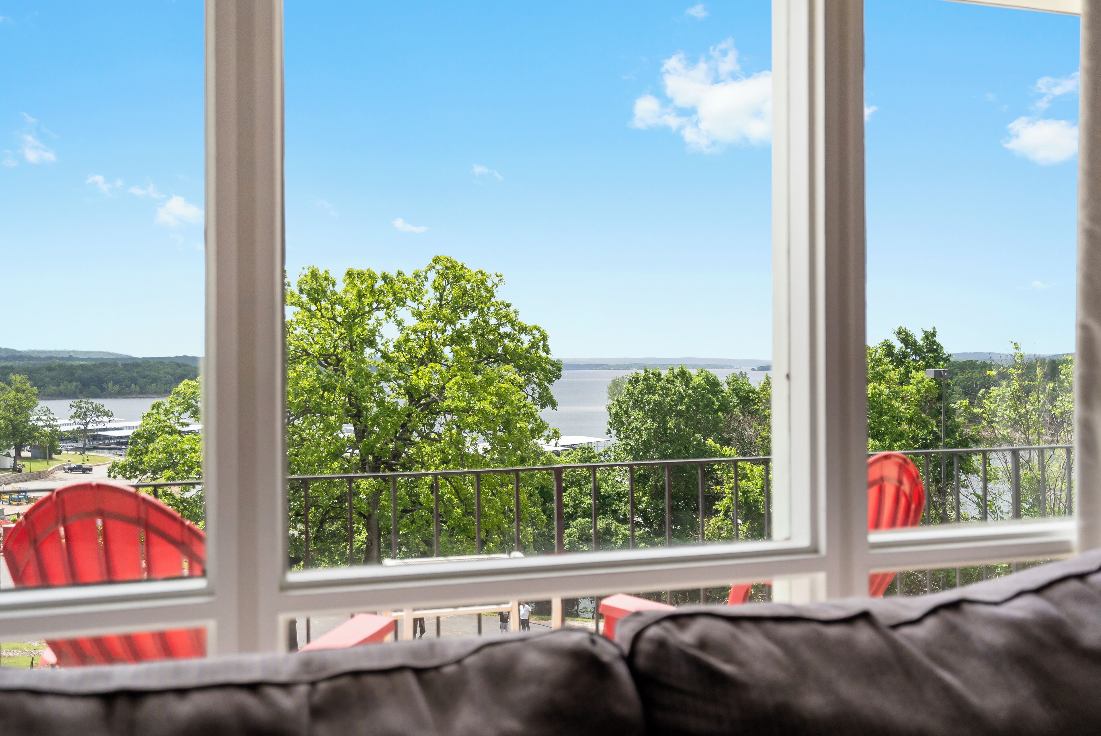 Habitación con vista a un lago y árboles a través de amplios ventanales.