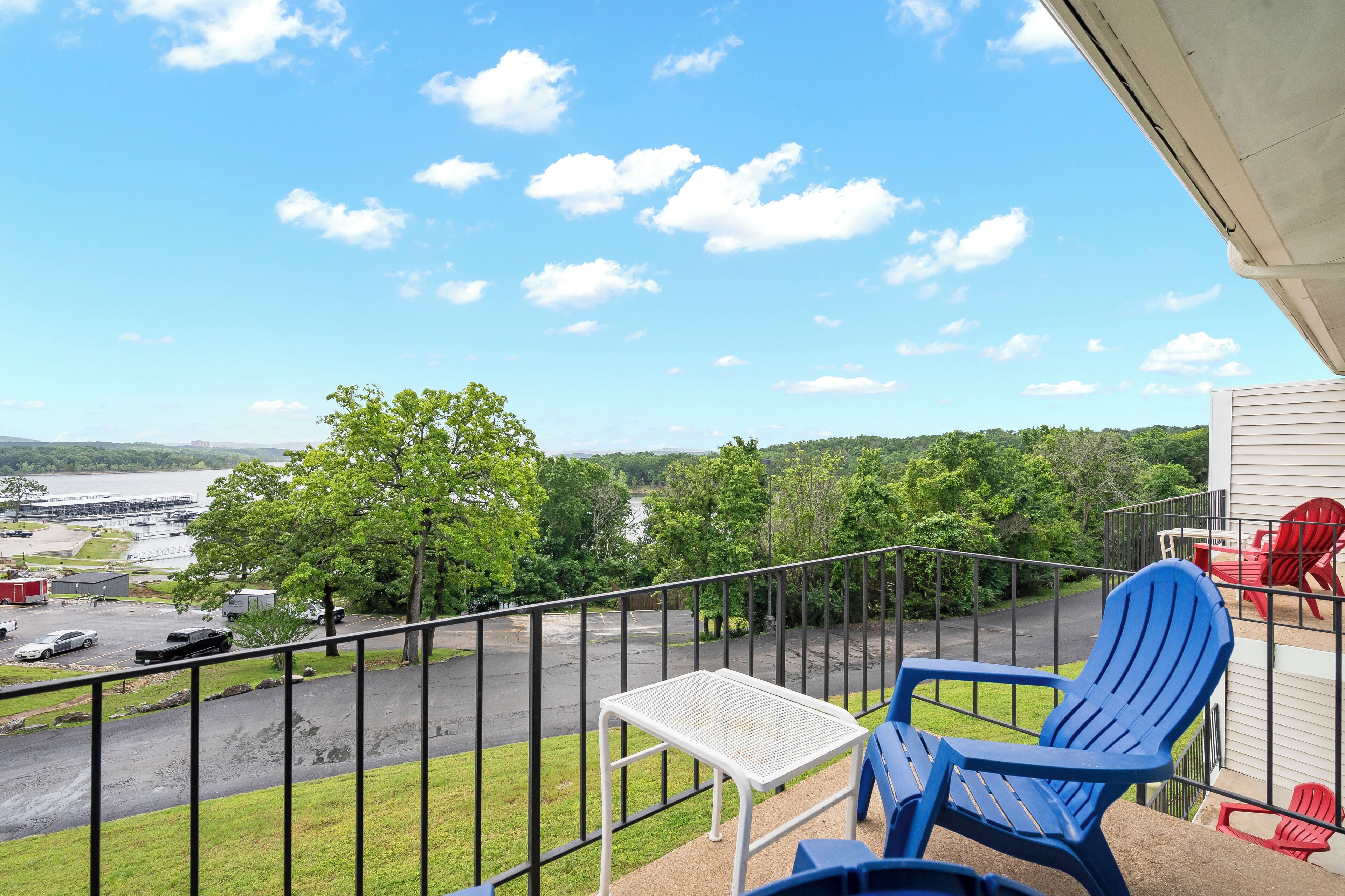 A balcony with a view of a parking lot and a body of water.