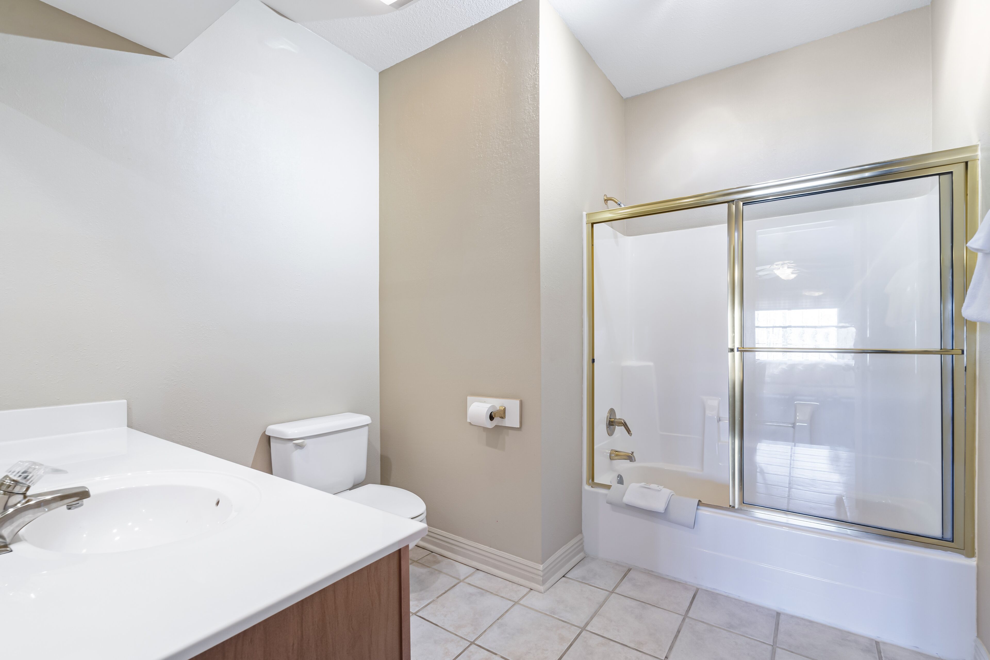A bathroom with a white sink, toilet, and a glass-enclosed shower.