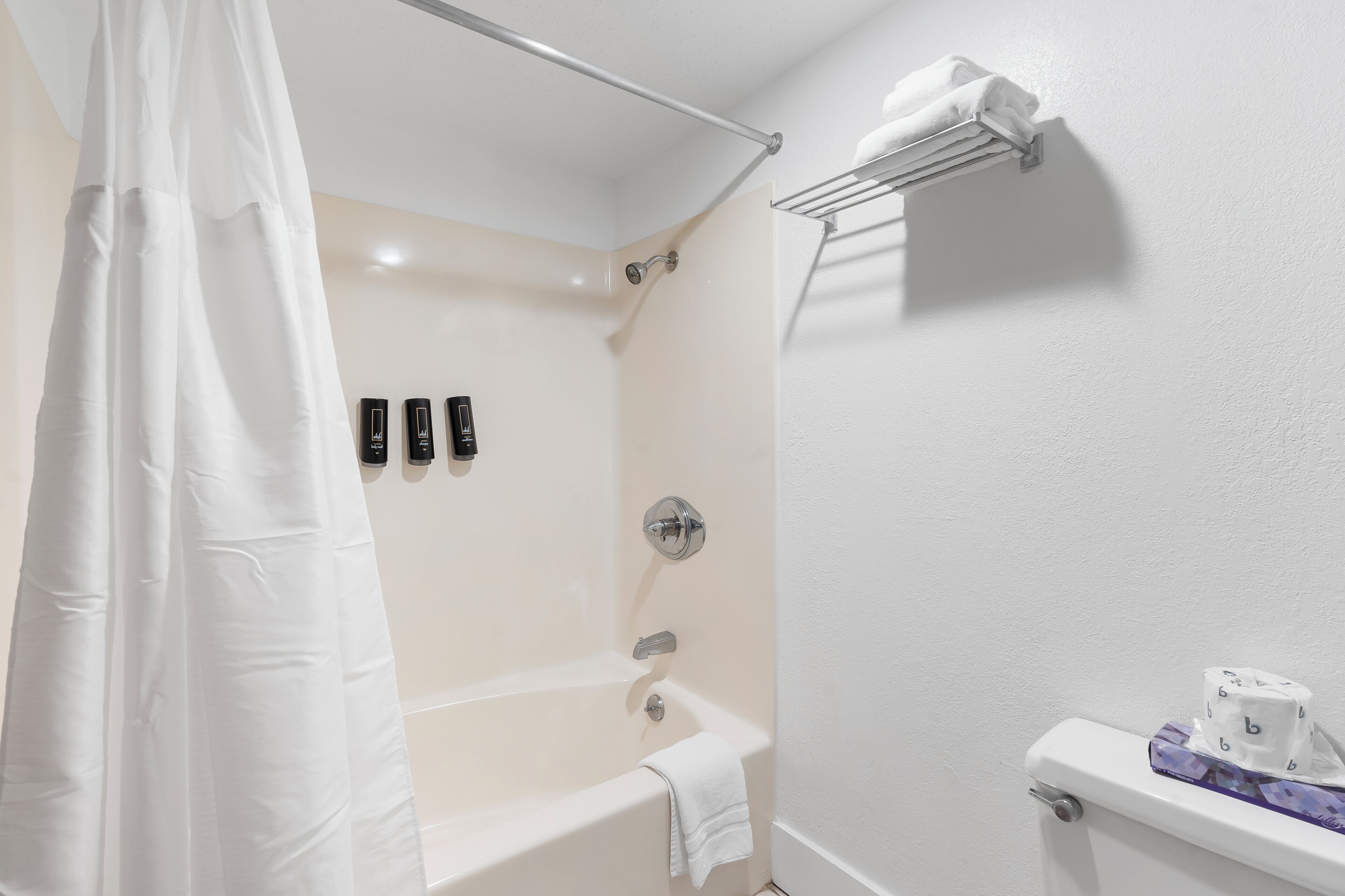 Ein Badezimmer mit Badewanne, Duschvorhang, Handtuchhalter und Toilette.