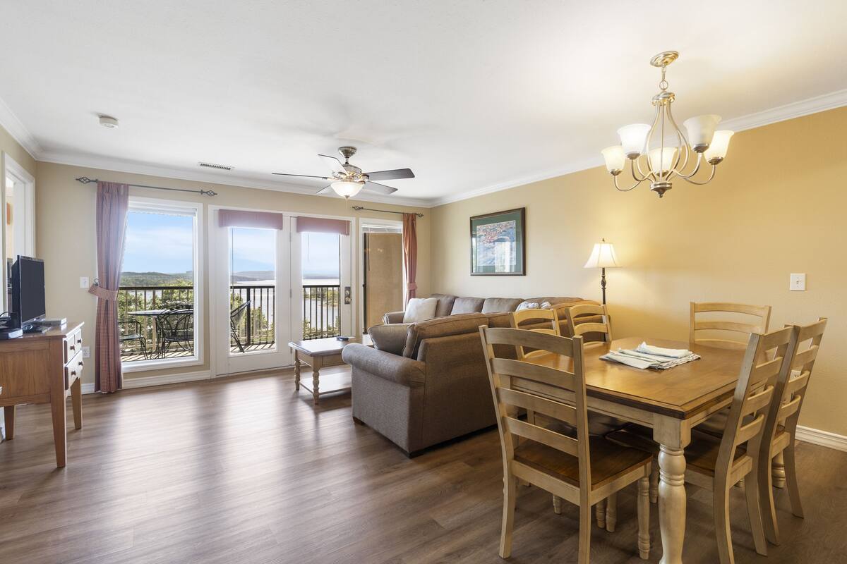 Un vaste espace de vie comprenant une table à manger en bois, des chaises, un canapé et un ventilateur de plafond.