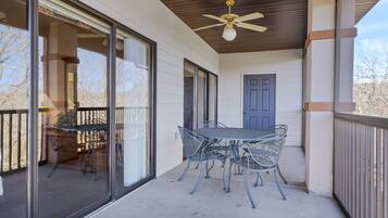 A covered patio with a table and chairs, a ceiling fan, and a door.