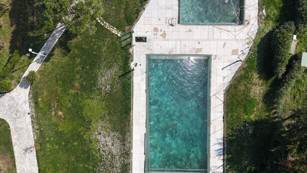 An aerial view of a property with two rectangular swimming pools surrounded by a tiled deck, with a pathway leading to a building. - M375 - Marcelli, two-room apartment with garden in a residence with swimming poo (Numana)