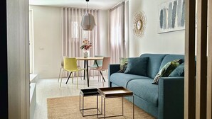 Een woonkamer met een bank, stoelen, een tafel en een hanglamp.