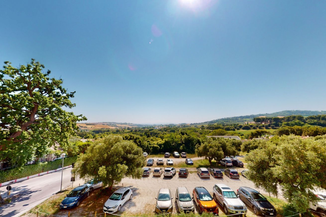 A parking lot with various cars and a clear view of the surrounding landscape.