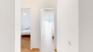 Ein schmaler Flur, der zu einem Schlafzimmer mit Bett und Nachttisch führt.