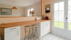 A kitchen with a wooden countertop, two bar stools, a white fridge, and a window with a view of the outdoors. - La Merisolle - 850m mer - Wifi (Pornic)