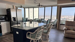 Una cocina moderna con una isla grande, taburetes de bar y un comedor con vistas.