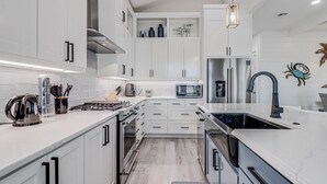 A modern kitchen with white cabinets, stainless steel appliances, and a grey countertop.
