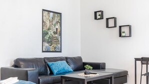 A modern living room with a leather sofa, a coffee table, and a framed painting on the wall. - Budget City Living: 1BR w/ Private Garden (Wien)