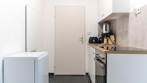 A compact kitchen with a refrigerator, stove, and coffee maker. - Budget City Living: 1BR w/ Private Garden (Wien)