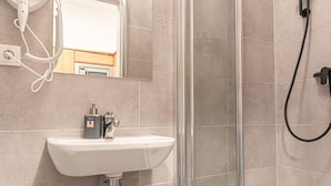 A bathroom with a white sink, a mirror, and a glass shower enclosure.