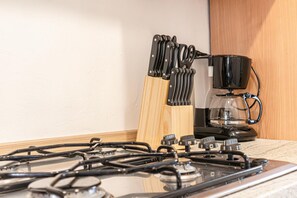 Uma cozinha com fogão a gás, cafeteira e porta-facas.