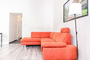 A modern living room with a sectional sofa, a floor lamp, and a framed picture on the wall.