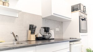 A modern kitchen with a sink, coffee maker, and oven. - Charming 1BR Apt. Near U6 Station am Schöpfwerk (Vienna)