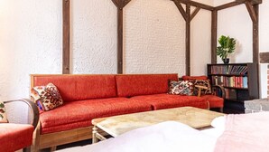 Ein gemütliches Zimmer mit einem roten Sofa, einem Holztisch und einem Bücherregal.