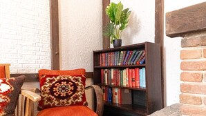 Ein gemütlicher Lesebereich mit Stuhl, Bücherregal und einer Topfpflanze.