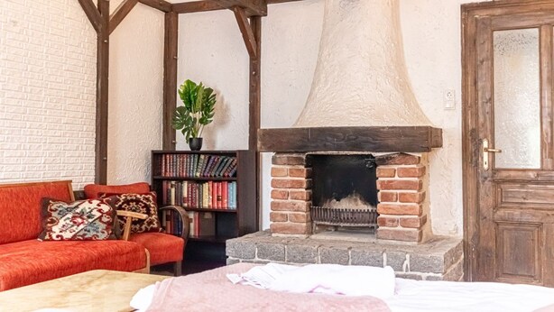 Ein gemütliches Zimmer mit Kamin, Bücherregal und einem roten Sofa.