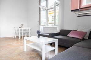 Moderni olohuone, jossa on valkoinen sohvapöytä, harmaa sohva ja valkoiset tuolit.