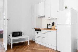 A compact kitchen with white cabinets, a microwave, a coffee maker, and a refrigerator.