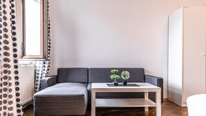 Un salon moderne avec un canapé gris, une table basse blanche et deux plantes en pot.