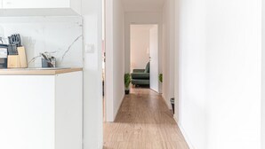 Un couloir avec un comptoir de cuisine, une chaise verte et une plante.