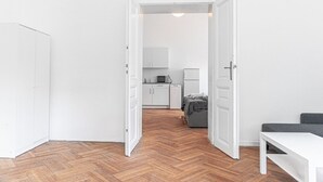 Une pièce avec un parquet en chevrons, des murs blancs, un lit, un bureau et une armoire.