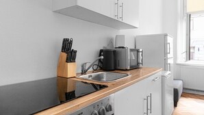 Une cuisine moderne avec un plan de travail noir, un évier en acier inoxydable et des armoires blanches.