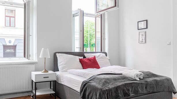 Une chambre à coucher avec un lit, une table de chevet, une fenêtre et un radiateur.