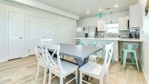 Une cuisine moderne avec des meubles blancs, un plan de travail gris et des chaises de couleur turquoise.