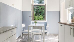 A kitchen with a window, white cabinets, and a table with chairs.