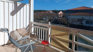 A balcony with a white railing, a red table, and two chairs. - Bel Appartement Centre Biscarrosse Plage (BISCARROSSE)