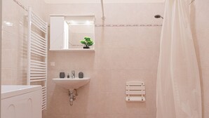 Ein Badezimmer mit weißem Waschbecken, einem Spiegel, einem Handtuchhalter und einer Duschvorhang.