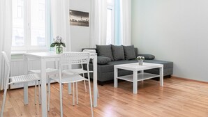 Ein modernes Wohnzimmer mit einem weißen Tisch, Stühlen, einem grauen Sofa und einem weißen Couchtisch.