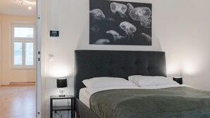 Ein Schlafzimmer mit einem großen Bett, zwei Nachttischen, einer Wandleuchte und einer Deckenleuchte.