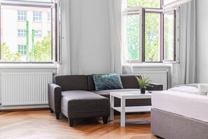 A modern room with a grey sofa, a white coffee table, and a bed.