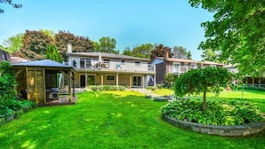 Een woonhuis met een verzorgd gazon, een overdekt terras en een tuin met diverse planten.