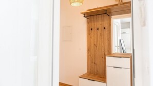 Ett rum med en garderob i trä, en spegel och en hängande lampa.